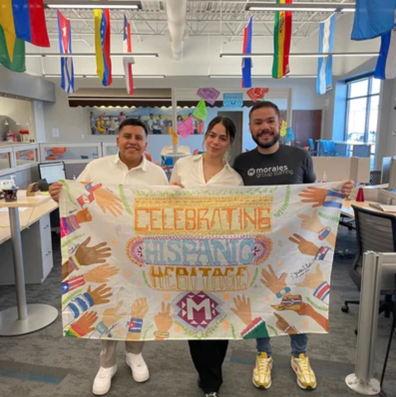 Morales Group Staffing teammates hold up flag drawn in celebration of Hispanic Heritage Month.