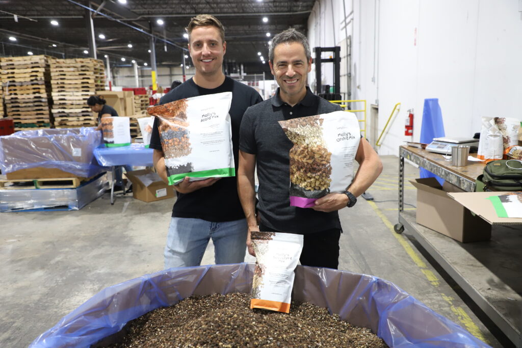 Jordan Socran and Tom Clegg holding their Molly's Aroid Potting Mix packaged by Acción Performance team.